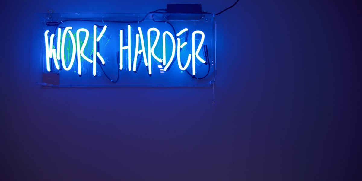 Scritta neon che dice"Work Harder"