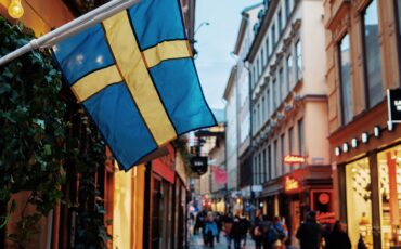 Immagine di una via in un centro storico con la bandiera gialla e blu svedese
